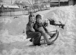 Kinder mit Schlitten vorm Haus des Fotografen