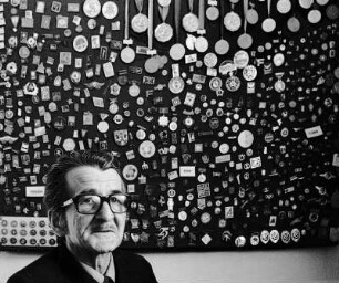 Pförtner vor Ordenwand : VEB Motorenwerk Wurzen. Portrait eines Pförtners vor einer Wand voller DDR Abzeichen, Auszeichnungen und Orden
