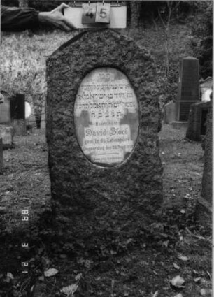 Grabstein 45 (Index: 99792517) Material: Granit, weiße Marmorplatte Zustand: gut Maße HxBxT: 128x57x31 cm Beschreibung: Stele, giebelartiger Abschluß, ovale Schriftplatte: Grabstein 45
