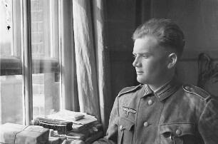Zweiter Weltkrieg. Niederlande unter deutscher Besatzung. Deutscher Wehrmachtsangehöriger am Fenster eines Dienstzimmers (wohl bei Den Haag)