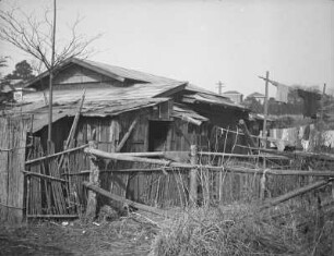 Bretterbude in der Vorstadt (wahrscheinlich von Tokio) : Bretterbude in der Vorstadt (wahrscheinlich von Tokio). Ansicht mit Verschlag und Zaun