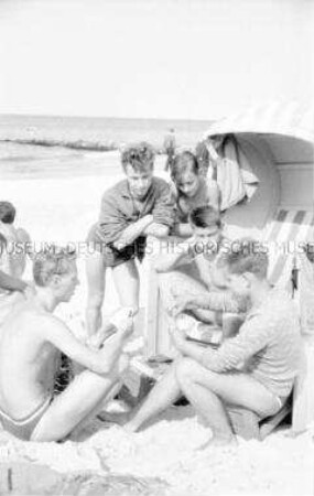 Junge Urlauber beim Kartenspielen am Strand von Zingst