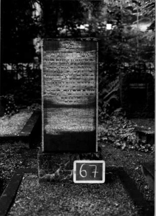 Grabstein 67 (Index: 100110293) Material: Granit Zustand: verwittert Maße HxBxT: 117x44x15 cm Beschreibung: Stele, Sockel, flacher Abschluß: Grabstein 67