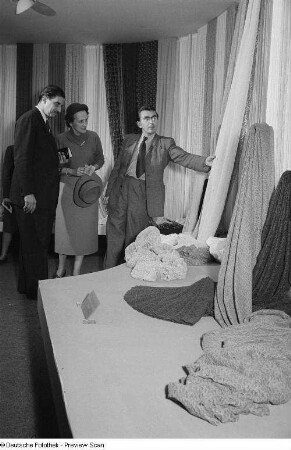 Drei Personen begutachten eine Textilie der Leipziger Herbstmesse 1954