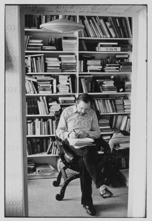 Der Schriftsteller Heinz Czechowski schreibend vor einem Bücherregal sitzend, aufgenommen in seiner Wohnung in Halle-Neustadt