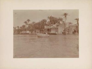 Häuser am Tigris : Flusslandschaft des Tigris zur Zeit der Überschwemmung mit Häusern am Ufer in der Nähe von Bagdad. Im Vordergrund sechs Männer in einem reifenähnlichen Boot.