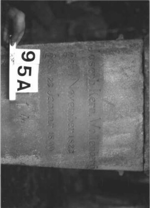 Grabstein 95 (Index: 99898135) Material: Sandstein Zustand: gut erhalten, Sockel etwas angewittert Maße HxBxT: 68x62x22 cm Beschreibung: aufgesockelte Stele mit Giebelaufsatz, im Giebelfeld Lorbeerkranz mit Schleife, unterer Sockel felsartig gearbeitet Symbolik: Lorbeerkranz: Grabstein 95A
