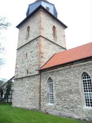 Evangelische Kirche - Kirchturm von Nordosten mit Schießscharten (Schlitzscharten) im Mittelgeschoß und gotischer Glockenstube sowie Langhaus