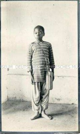 Porträt eines Jungen der Missanga in der Bekleidung eines Hausjungen vor neutralem Hintergrund