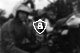 Autobahnparkplatz: Polizeihauptmeister [Name maskiert] mit Funkmikrofon an seinem Dienstmotorrad