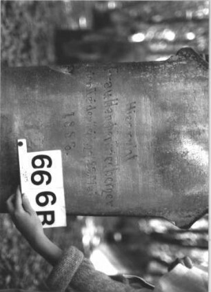 Grabstein 666 (Index: 99900567) Material: Sandstein Zustand: stellenweise verwittert Maße HxBxT: 123x45x18 cm Beschreibung: aufgesockelte Stele mit oben abgeflachtem Dreiecksaufsatz, im Dreiecksfeld Levitenkanne, daneben Eckakroterien, Schriftfeld von Zackenfries umgeben Symbolik: Levitenkanne, Zackenfries Besonderheit: Levitenkanne auf einem Frauengrab ?: Grabstein 666B