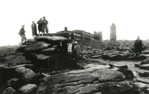 Harz. Brockengipfel. Touristen am Teufelstuhl gegen Hotel, Meteorologische Station und Aussichtsturm