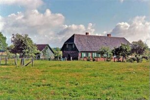 Neverstaven: Landarbeiterkate: Mehrfamilienkate aus Backstein, Traufseite, Giebelseite: vorne Weide, Zäune, hinten links Scheune