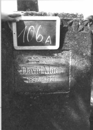 Grabstein 106 (Index: 100114122) Material: Kalkstein Zustand: verwittert Maße HxBxT: 123x85x20 cm Beschreibung: konische Stele, flacher Abschluß, Schriftfeld rechteckig Symbolik: vierzackiges Sternenfries: Grabstein 106A