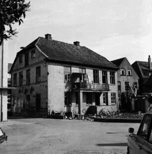 Abrisshäuser: Rückansicht: davor Bretter und Bauschutt: vorn Hof mit Pkws [angeschnitten]: links Gebäudeecke und Durchgang zur Straße