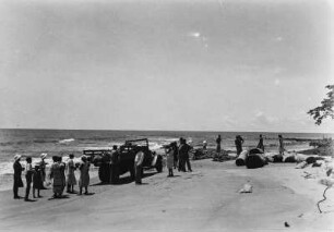 Strandansicht : Automobil und Personen an einem Strand.