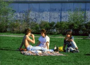 Jugendliche sitzen auf einer Wiesen im Stadtbezirk Zehlendorf in Berlin-West direkt vor der Mauer, Foto ca. 1985