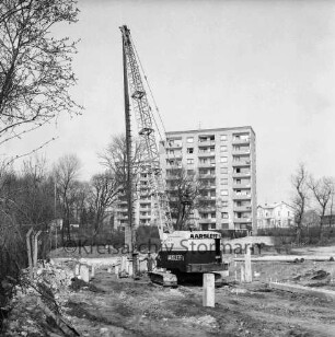 Sülzberg: Bau mehrgeschossiger Wohnblocks: Ramme beim Setzen von Pfählen: links daneben Arbeiter: links Zaun: hinten Mitte Hochhäuser am Kurpark: hinten rechts Wohngebäude und Betriebsgelände der Maschinenfabrik Lythall KG