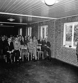 Volksschule: Schultwiete: Erweiterungsbau: Einweihung: Pausenhalle: Blick auf Stuhlreihen mit Gästen