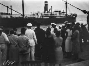Personen am Kai : Personen am Kai beobachten das Auslaufen eines Schiffes