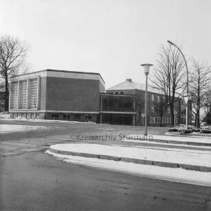 Erweiterungsbau [später Gebäude C] mit Kreistagssitzungssaal: vor Fertigstellung: vorn Busbahnhof und Mommsenstraße: hinten rechts Reimer-Hansen-Straße: links Bäume: dahinter Hauptgebäude [später Gebäude A]: Winter