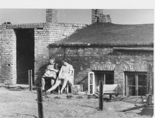 Im zerstörten Hamburg ist Wohnraum auch 1950 noch knapp. In Trümmern hergerichtete Unterkünfte nutzen Hamburger als Wohnungenn - wie in Billstedt, einem 1943 stark zerstörten Stadtteil. Frauen sitzen vor einer Kellerwohnung