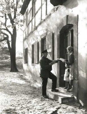 Briefträger, die Post einer Frau mit kleinem Mädchen übergebend