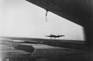 Militärflugzeug : Ein Militärflugzeug begleitet das Luftschiff LZ 127 Graf Zeppelin vor Leningrad, heute Sankt Petersburg. Am Boden landwirtschaftlich genutze Flächen.
