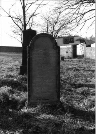 Grabstein 30 (Index: 100116127) Material: Sandstein Zustand: verwittert mit teilweisem Textverlust Maße HxBxT: 118x68x21 cm Beschreibung: aufgesockelte Stele mit eingezogenem Rundbogenabschluß, eingetieftes Schriftfeld: Grabstein 30