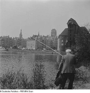 Danzig. Blick auf die Rechtsstadt mit Krantor und über den Fluss Mottlau, im Vordergrund ein Angler