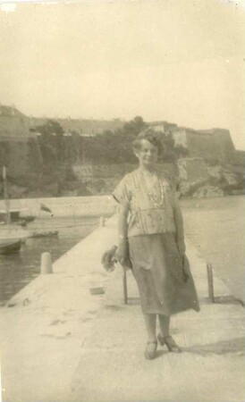Die Bildhauerin Etha Richter im Sommerkleid auf dem Kai in einem Hafen