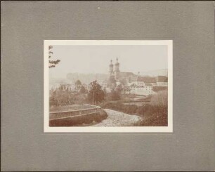 Kirche und Kloster, davor rauchende Häuserruinen.