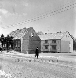 Schönningstedter Straße: links altes Wohnhaus aus Backstein: davor Bäume: in der Mitte Frau: hinten rechts Neubau eines Wohnblocks: Winter