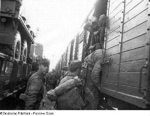 Deutschland . Truppenübungsplatz Klietz. Nationale Volksarmee - Landstreitkräfte. Truppenverlegung per Eisenbahnmarsch. Soldaten zwischen zwei Militärzügen (links Flachwagen mit Militärtechnik, rechts Mannschaftswagen)