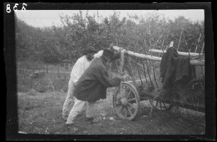 Odobești (=Rumänien): 2 Rumänen am Gestänge neben einem Leiterwagen, im Hintergrund eine kleine Obstplantage (?)