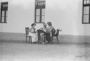 Drei Frauen : Drei Frauen sitzen um einen Tisch und unterhalten sich.