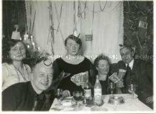 Fünf Personen bei einer privaten Silvesterfeier in einem mit Fünftausend-Mark-Scheinen dekorierten Wohnzimmer