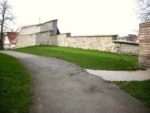 Kirchhof im Norden mit erhaltenem Abschnitt der wehrhaften Kirchhofmauer - Steinbrüstung mit Schießscharten saniert-hölzerner Laufgang und Regendach nicht ergänzt