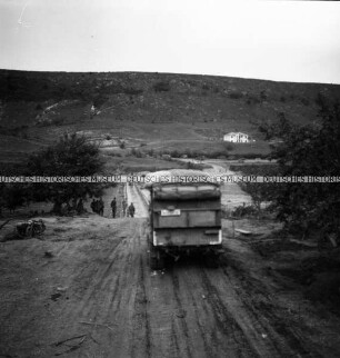 LKW der Wehrmacht auf einer zerfahrenen Landstraße in hügeliger Landschaft