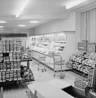 Peters Delikatessen: Mühlenstraße, Ecke Hindenburgstraße: Feinkostgeschäft: Innenaufnahme: Blick in Verkaufsraum: Regale mit Waren, Kühltheke, Einkaufswagen, Einkaufskörbe: vorne Kasse