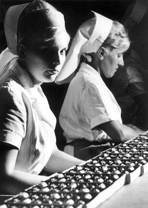 Saarlouis. Trumpf Schokoladenfabrik. Arbeiterinnen beim Befüllen von Bonbonieren mit Pralinen, Aufgenommen 1964