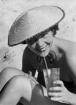 Model Helga am Strand der Ostsee. Ein kühler Drink tut bei der Hitze gut.