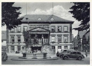 Rathaus Detmold mit Donopbrunnen, daneben stehen Autos, Sommertag