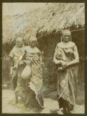 Drei Massai-Frauen vor einer Hütte