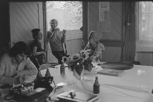 Höfgen. Akt-Pleinair 1979. Die Fotografen Eva Mahn, Günter Rössler und andere Teilnehmer im Gespräch, am Tisch sitzend ein Fotomodell mit Turban