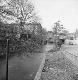 Trave: Stadtarm: rechts Parkfläche mit Pkw: links ehemaliges Fabrikgebäude Richtung Schultwiete: hinten Fußgängerbrücke