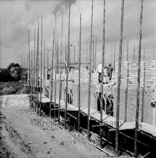 Herrenhusen: Wohnsiedlung mit Reiheneigenheimen in Bau: Rohbauten mit Gerüst, Arbeiter: Stapel mit Mauersteinen: unbefestigter Baustellenweg: im Hintergrund links Wohnhaus an Ahrensböker Straße