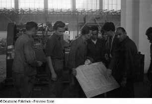 Mehrere Personen studieren eine technische Zeichnung beim Aufbau des chinesischen Pavillons für die Herbstmesse 1953