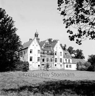 Kloster Nütschau: Herrenhaus: Restaurierung der Südfront: Gerüst vor Mittelflügel: davor Baumaterial: vorn Rasenfläche: rechts und links Bäume