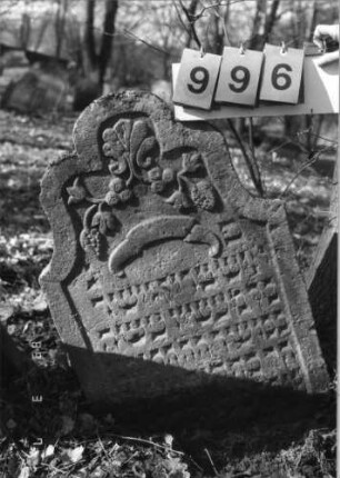 Grabstein 996 (Index: 99751346) Material: Sandstein Zustand: gut, Stele eingesunken Maße HxBxT: 83x56x10 cm Beschreibung: Stele, geschweift eingezog. Rundbogenabschl. , Schriftfeld eingetieft Symbolik: Trauben, Muschel, Feigen, Ranken: Grabstein 996